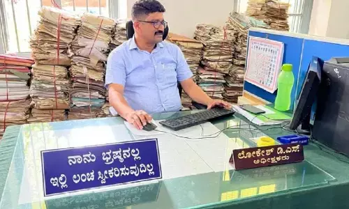 ಹಾಸನ | ನಾನು ಭ್ರಷ್ಟನಲ್ಲ, ಇಲ್ಲಿ ಲಂಚ ಸ್ವೀಕರಿಸುವುದಿಲ್ಲ ಎಂದು ಬೋರ್ಡ್ ಹಾಕಿಕೊಂಡ ಅಧಿಕಾರಿ