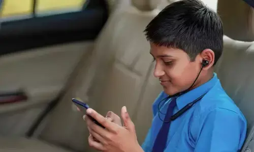 child sitting in car and using smartphone