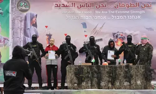 Israeli captives Tal Shoham, second from left, and Avera Mengistu, fourth from right, are flanked by Hamas fighters as they stand on a stage during their release in Rafah, Gaza [