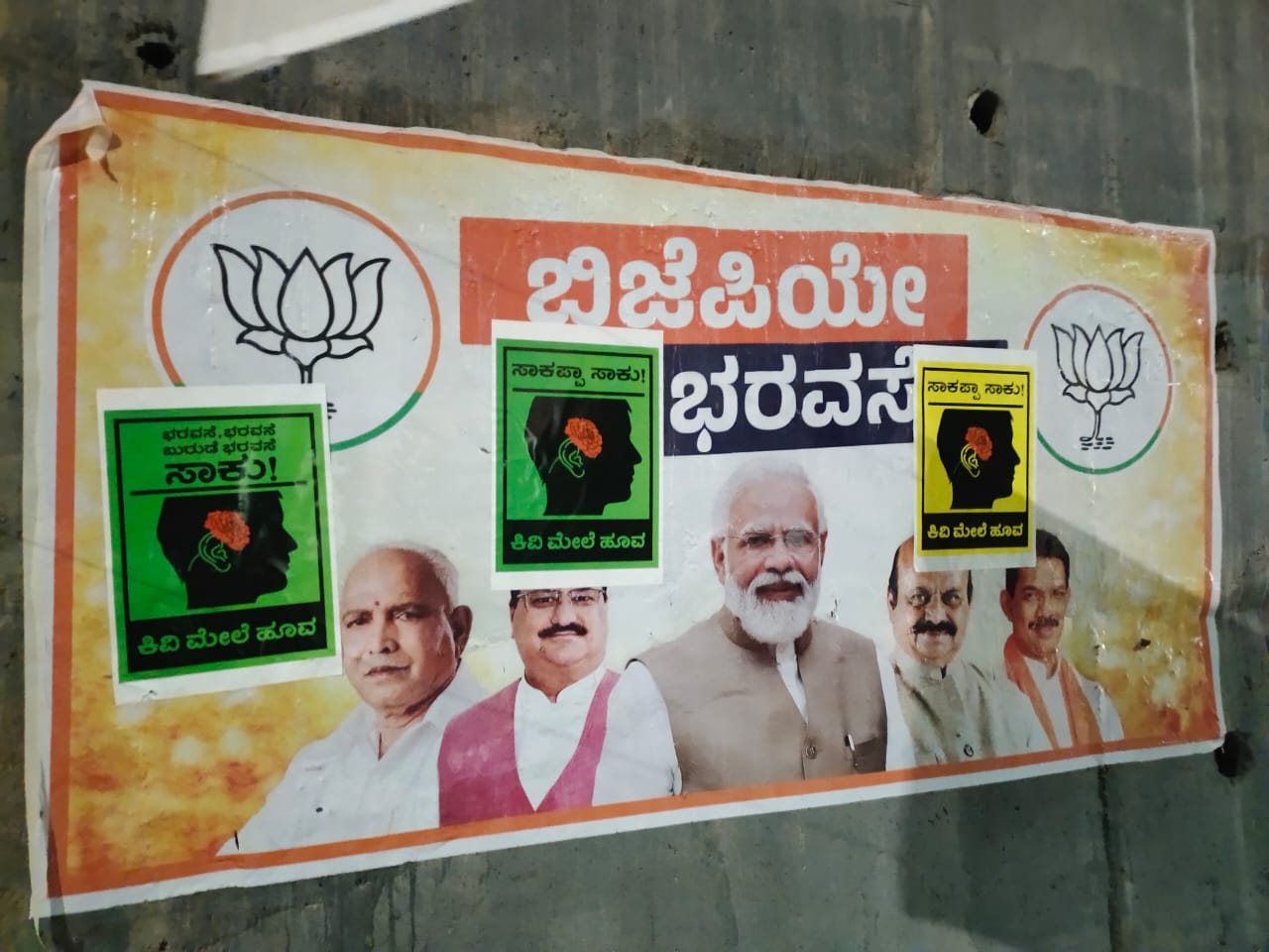ಬಿಜೆಪಿಯ ಭರವಸೆಯ ಪೋಸ್ಟರ್‌ ಗಳ ಮೇಲೆ ಕಿವಿ ಮೇಲೆ ಹೂವು ಪೋಸ್ಟರ್‌ ಪ್ರತ್ಯಕ್ಷ