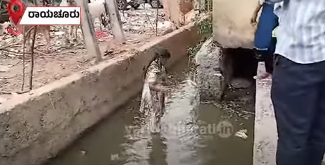 ರಾಯಚೂರು | ಸಫಾಯಿ ಕರ್ಮಚಾರಿಗಳಿಗೆ ಸ್ಮಶಾನ ಭೂಮಿ ನೀಡಲು ಒತ್ತಾಯ: ರಾಜಕಾಲುವೆಯಲ್ಲಿ ಕುಳಿತು ಮಹಿಳೆ ಪ್ರತಿಭಟನೆ